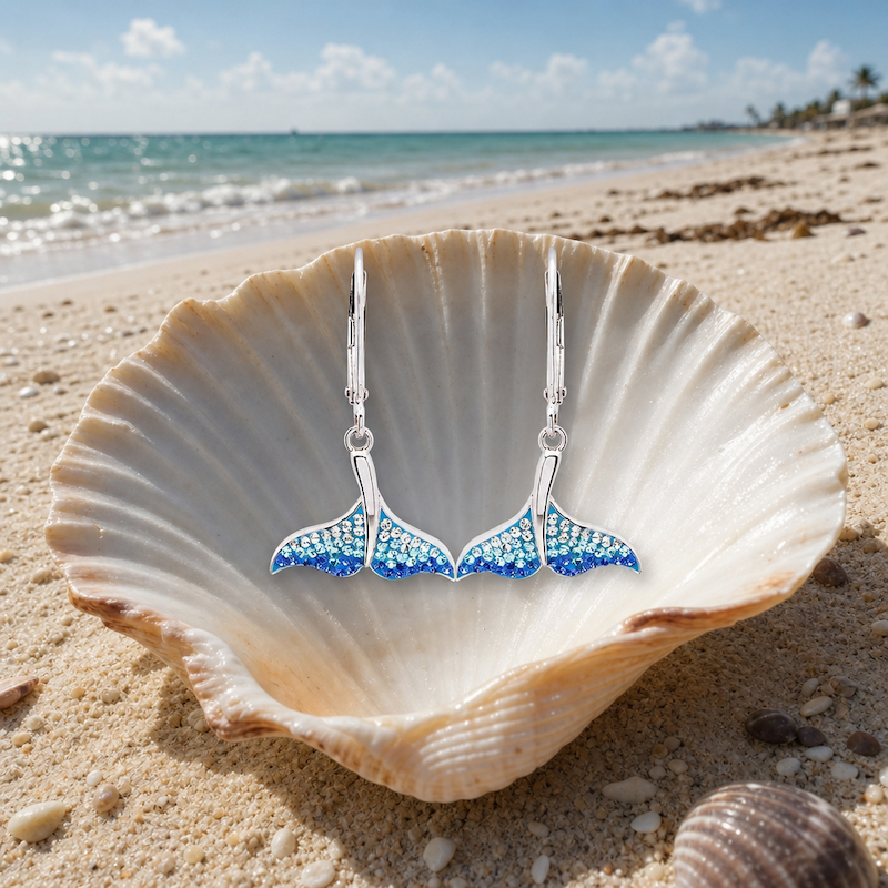 Sterling Silver Whale Tail Earrings with Ombre Blue Crystals in a seashell on the beach